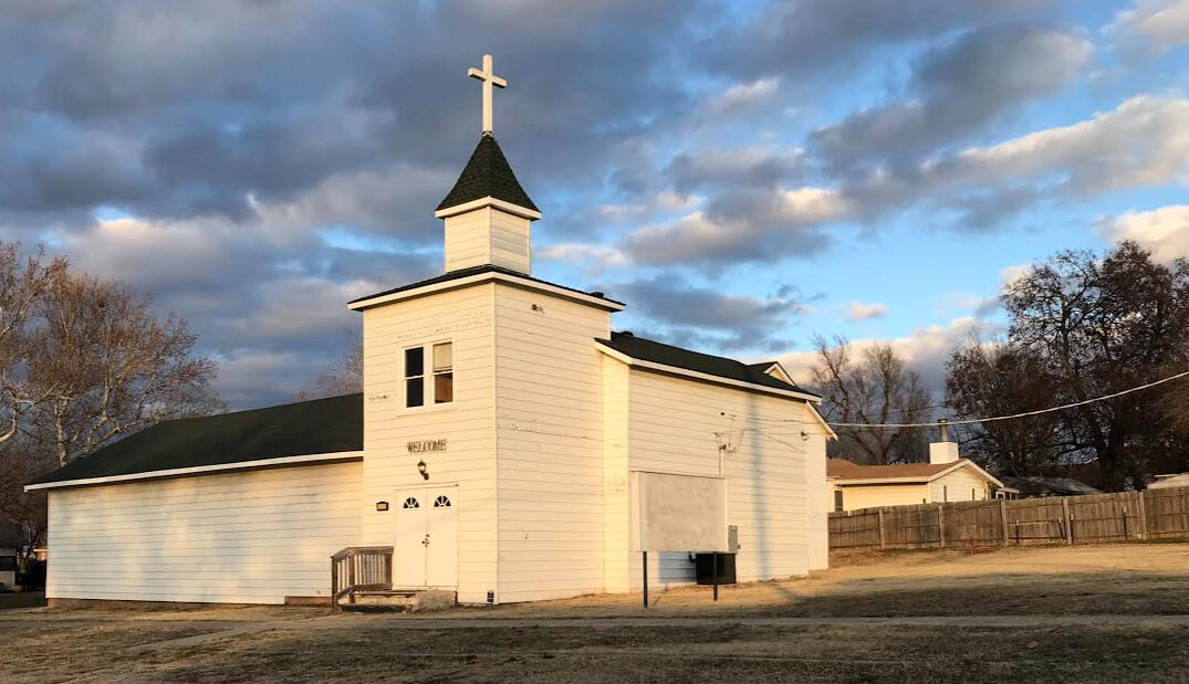 Exterior of Saint Cate’s Route 66 Folk Art Cathedral, a historic white clapboard church in Yukon, Oklahoma, beneath a dramatic Oklahoma sky.
